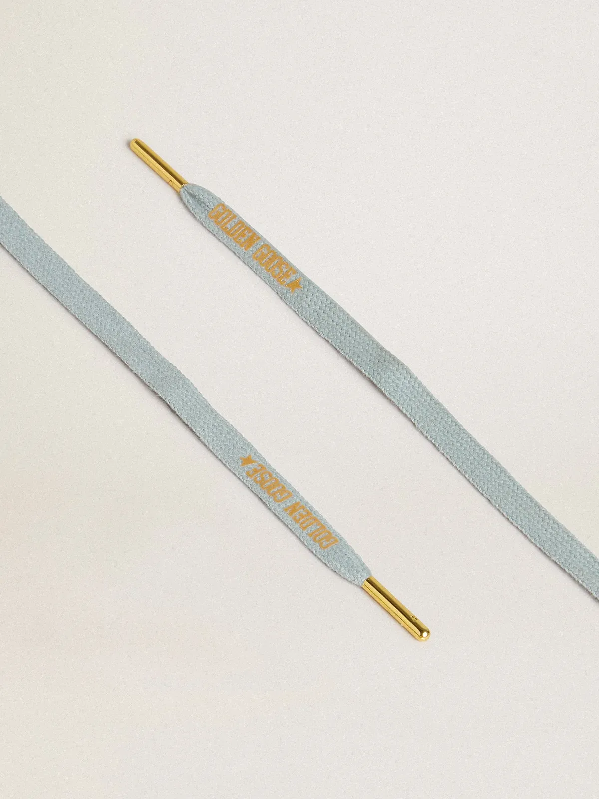 Cordones de algodón celeste con logotipo dorado en contraste